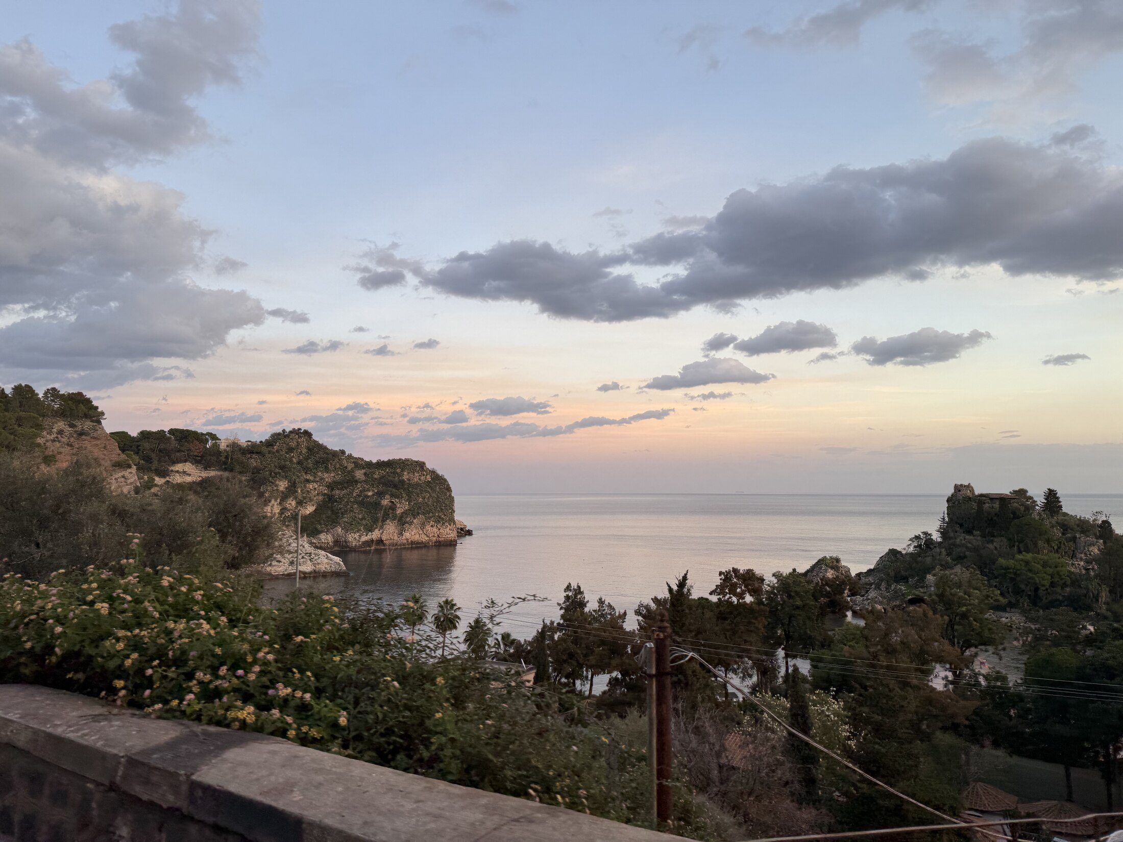 A sheltered Sicilian cove beneath a soft evening sky